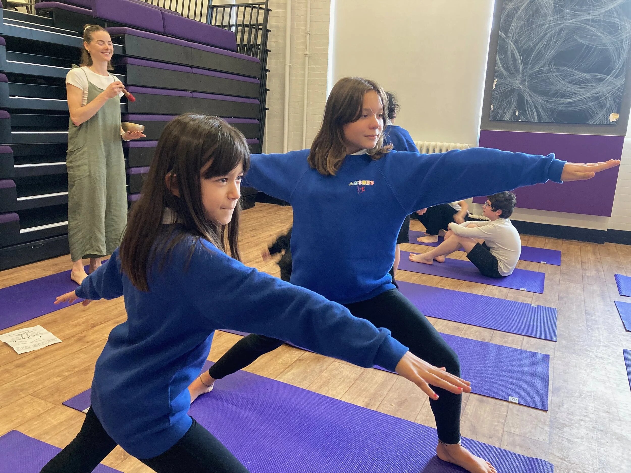 Children in warrior pose in a school hall