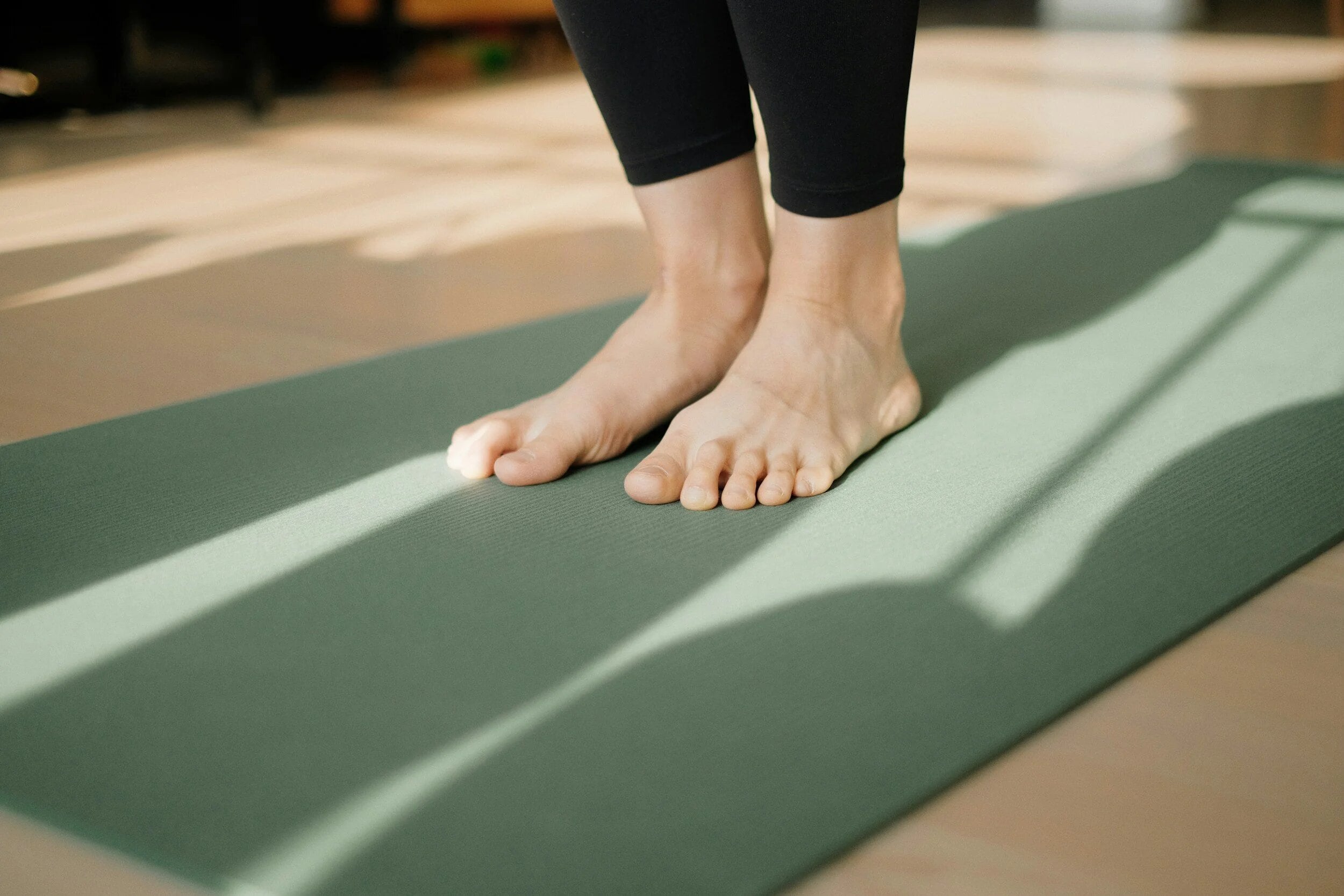 Bare feet on a yoga mat in sunlight