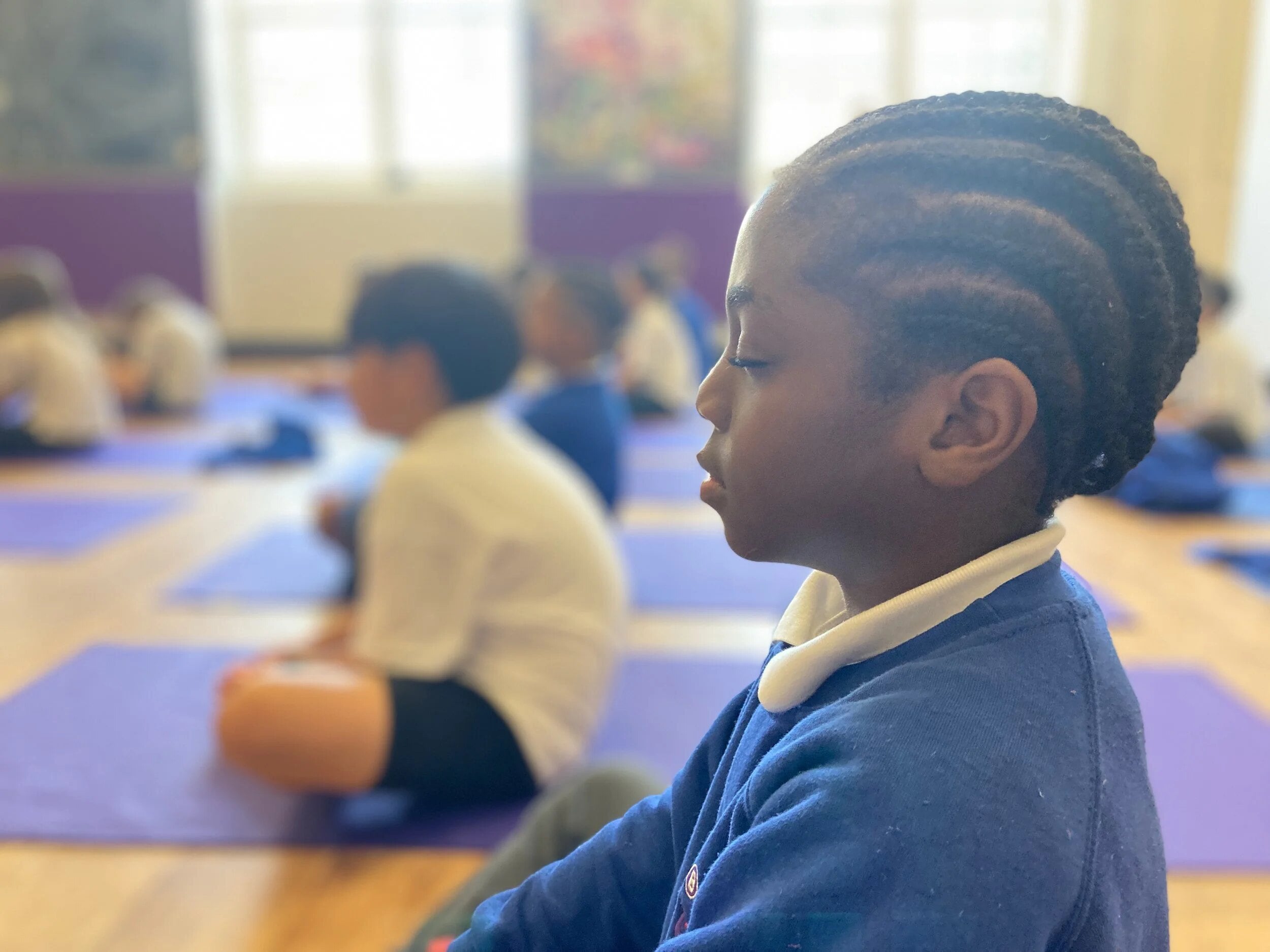 A child sitting calmly on a yoga mat